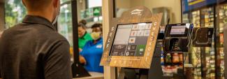 Customer using self checkout at Breeze Thru convenience store